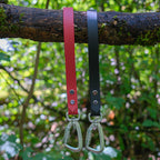 Poignées de harnais pour chien en Biothane rouge et noir suspendues à une branche, mousquetons aluminium